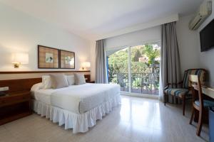 a bedroom with a white bed and a balcony at Hotel Piedra Paloma in Estepona