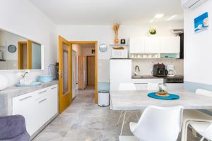 a kitchen with white cabinets and a table and chairs at Mukalba - Emira in Medulin
