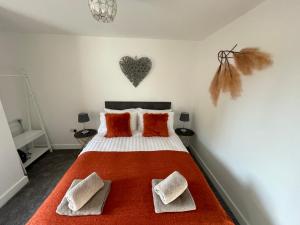 1 dormitorio con 1 cama con almohadas de color naranja y un corazón en la pared en Luxury One Bed Apartment Stevenage en Stevenage