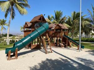 a playground with a slide in a park with palm trees at منتجع هوانا، صلالة , عمان in Wādī Khasbar
