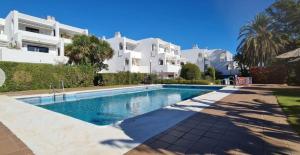 a swimming pool in front of a large white building at Sotogrande Duplex near Polo, 2 terraces, 2 pools, full south, 7' drive to beaches and Port, 4 people in Sotogrande