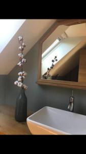 ein Badezimmer mit einem weißen Waschbecken und einer Vase mit Blumen in der Unterkunft La Grange du Colombier - Saint Geniez d'Olt et d'Aubrac in Saint-Geniez-dʼOlt