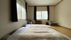 a bedroom with a large bed with two windows at Bear Elephant in Rausu