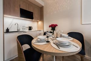 a dining room table with chairs and a kitchen at Aurum Aparthotel - Nowe Apartamenty blisko Plaży - Neue Appartements in Strandnähe in Świnoujście