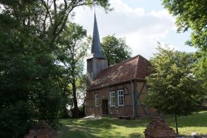 an old brick church with a steeple on a field at Haus Seenplatte in Groß Nemerow