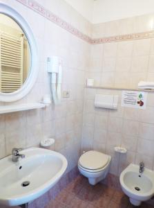 bagno con lavandino, servizi igienici e specchio di Hotel Crystal a Rimini
