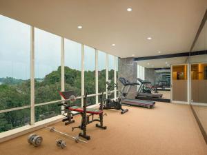 a gym with several exercise equipment in a room with windows at The Alana Yogyakarta Hotel and Convention Center in Yogyakarta