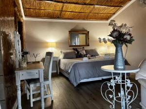 a bedroom with a bed and a table with a vase of flowers at Uitzicht Private Nature Reserve and Lodge in Fouriesburg