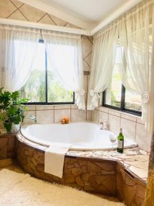 een groot bad in een badkamer met ramen bij Uitzicht Private Nature Reserve and Lodge in Fouriesburg