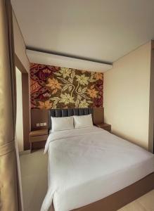 a bedroom with a large white bed with a painting on the wall at AJ BOUTIQUE HOTEL in Yogyakarta