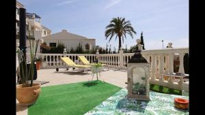 a patio with green grass and a table with a lantern at FREDOV in Benalmádena