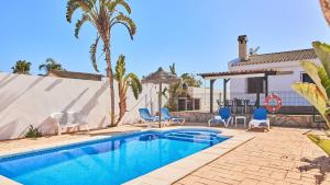 ein Pool mit blauen Stühlen und ein Haus in der Unterkunft Chalet El Cancelín Conil de la Frontera by Ruralidays in Conil de la Frontera