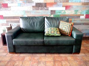 Un sofá de cuero verde con dos almohadas. en Hotel Langosteira, en Finisterre