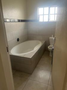 ein Bad mit einer Badewanne und einem WC in der Unterkunft 8 on twentieth in Brakpan