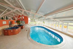 uma grande piscina interior com uma banheira de hidromassagem em Retro Lido - Vonyarcvashegy em Vonyarcvashegy