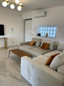 ein Wohnzimmer mit 2 weißen Sofas und einem Tisch in der Unterkunft Appartamento al Mare in Montepaone Lido