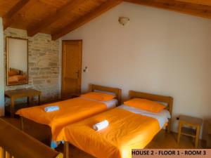 2 Betten mit orangefarbener Bettwäsche in einem Zimmer in der Unterkunft Villa Barbara - Orihi in Barban