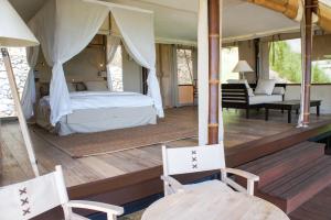 a bedroom with a bed and two chairs on a deck at Selong Selo Resort and Residences in Selong Belanak