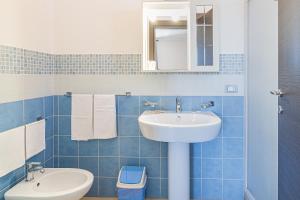 a blue tiled bathroom with a sink and a toilet at San Martino Apartment Sofia in Cassibile +14 photos