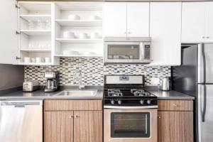 a kitchen with white cabinets and a stove top oven at Somerville 1BR w WD nr Assembly T BOS-757 in Somerville