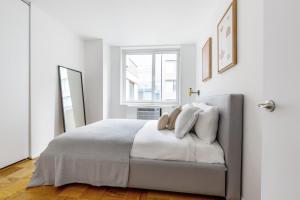 une chambre blanche avec un lit et une fenêtre dans l'établissement Midtown 1BR w Gym Doorman nr Central Park NYC-510, à New York