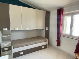 Schlafzimmer mit einem Bett, Schränken und einem Fenster in der Unterkunft Dimora Pina sul mare in Codaruina