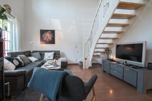 a living room with a couch and a tv and stairs at Ferienhaus Hafenresidenz in Greetsiel