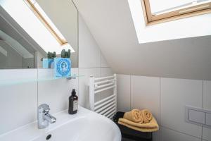 een badkamer met een witte wastafel en een dakraam bij Hafenparadies in Greetsiel