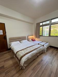 een slaapkamer met 2 bedden en een groot raam bij 觀心農舍 民宿 Ageless Farmhouse in Sanyi