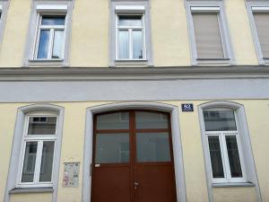 ein Gebäude mit einer braunen Tür und drei Fenstern in der Unterkunft Cozy 8-Person Home in Vienna Located at Haberlgasse 82 N1 in Wien