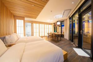 a bedroom with a large white bed and a table at Gwanganli The Club Hotel in Busan