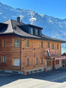 un grande edificio in legno con montagne sullo sfondo di Hotel Lakeview bei Interlaken a Interlaken
