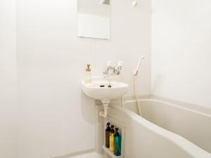 a white bathroom with a sink and a bath tub at 名護パークサイドコンドミニアムTKステイ in Nago