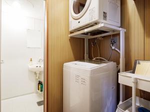 een wasmachine in een badkamer met een magnetron bij 名護パークサイドコンドミニアムTKステイ in Nago