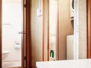 a bathroom with a sink and a toilet and a mirror at 名護パークサイドコンドミニアムTKステイ in Nago