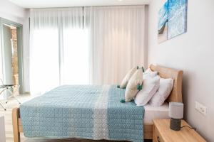 a bedroom with a bed with a blue blanket and pillows at Beach Deluxe House in Kos Town