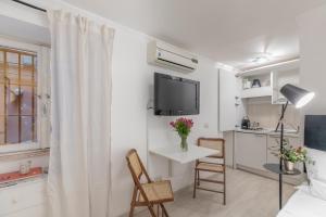 a white living room with a tv and a table and chairs at Basic Studio - 350 m far from Fontana di Trevi in Rome