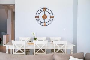a dining room with a white table and a large clock at Beach Deluxe House in Kos Town
