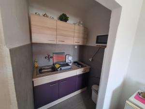 una piccola cucina con armadi viola e lavandino di Apartments Luči a Hvar