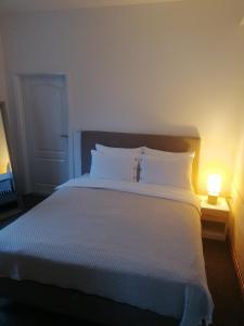 a bedroom with a large white bed with a lamp at Apartman Dukat in Višegrad
