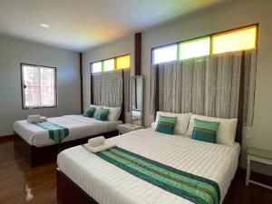 a bedroom with two beds and two windows at GrandmaD in Chiang Rai