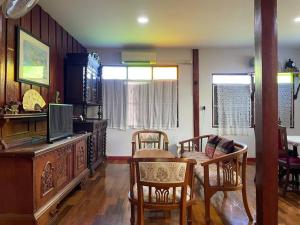 - un salon avec une table, des chaises et une télévision dans l'établissement GrandmaD, à Chiang Rai