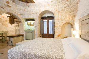 - une chambre avec un grand lit dans un mur en pierre dans l'établissement Trulli Holiday Albergo Diffuso, à Alberobello