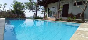 a large blue swimming pool next to a house at Maluk House in Taliwang