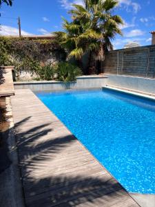 a blue swimming pool with a wooden walkway next to a house at 2 pièces rez-de-jardin dans maison avec piscine in Villeneuve-Loubet