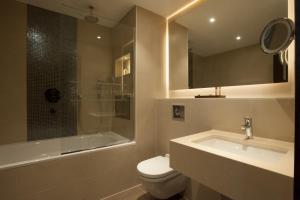 a bathroom with a sink, toilet and bathtub at St George's Hotel - Wembley in London