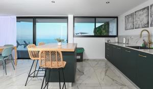 uma cozinha com armários pretos e uma mesa com cadeiras em Villa-SELAVI 3 unit complex with infinity pool em Tiberias