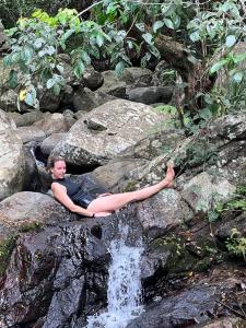 a woman laying on a rock next to a waterfall at The Woods in Haputale