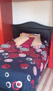 オタバロにあるCasa N Campestre en la naturaleza a las faldas del Taita Imbaburaのベッド(黒と赤の掛け布団、枕付)