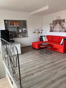 een woonkamer met een rode bank en een tafel bij 2 pièces rez-de-jardin dans maison avec piscine in Villeneuve-Loubet